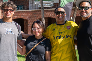 Four people pose in front of a residence hall that says, Welcome Home