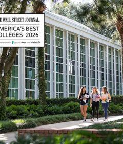 Three students walk past an academic building with a graphic that says Wall Street Journal's Best Colleges 2026