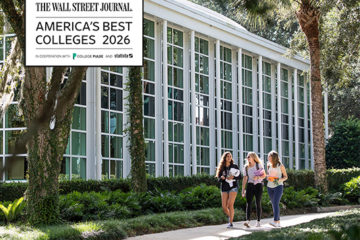 Three students walk past an academic building with a graphic that says Wall Street Journal's Best Colleges 2026