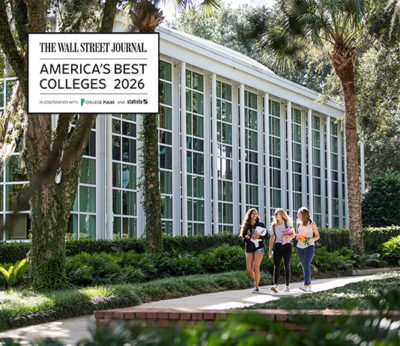 Three students walk past an academic building with a graphic that says Wall Street Journal's Best Colleges 2026