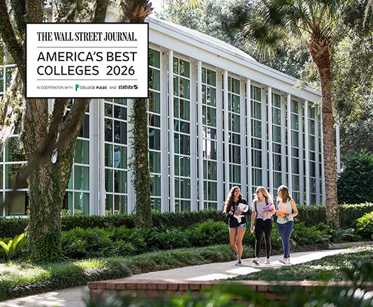 Three students walk past an academic building with a graphic that says Wall Street Journal's Best Colleges 2026