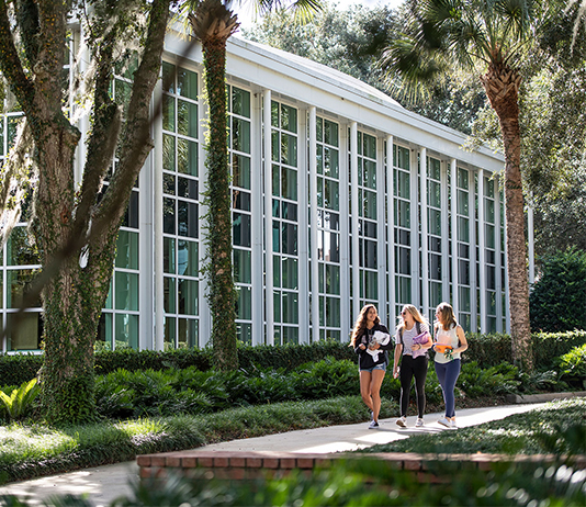 Three students walk by an academic building