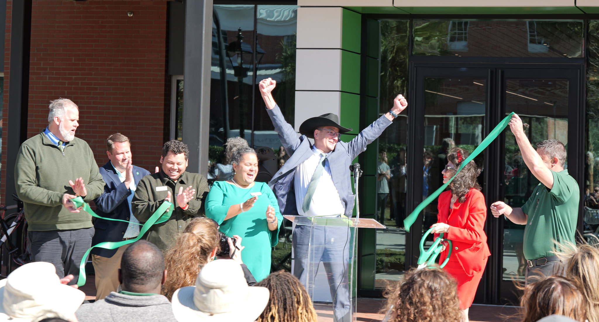 A crowd cuts the ribbon on a new building