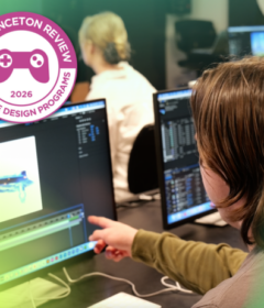 A student points at a computer screen with a graphic imposed that says Top Game Design School 2026