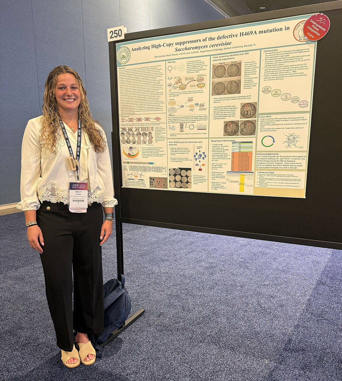 A woman poses next to a scientific poster board
