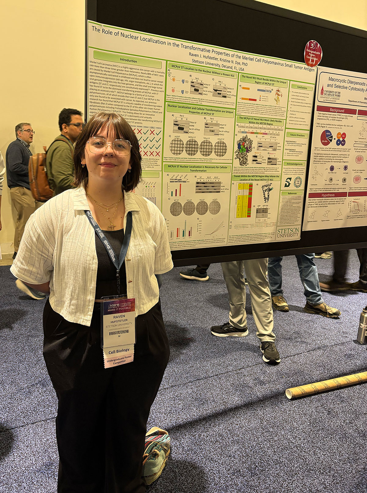 A woman poses beside a scientific poster board.