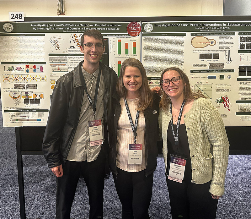 Three people pose in front of a scientific poster board.