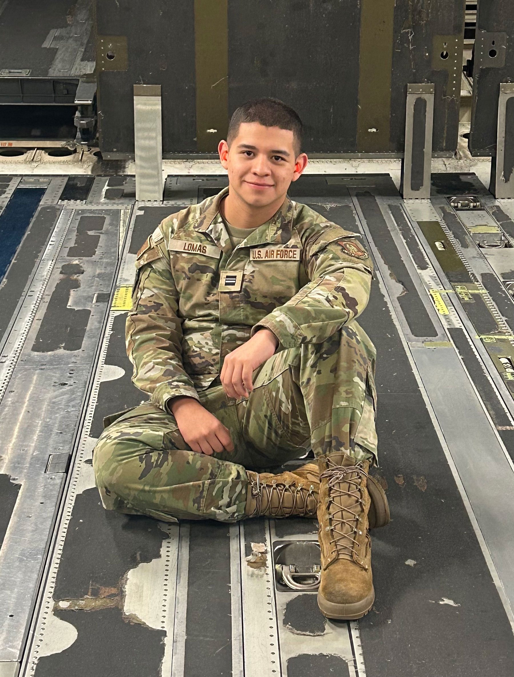 A young man sits in military fatigues.