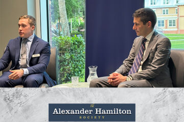 A photo of two men in suits, seated side by side.