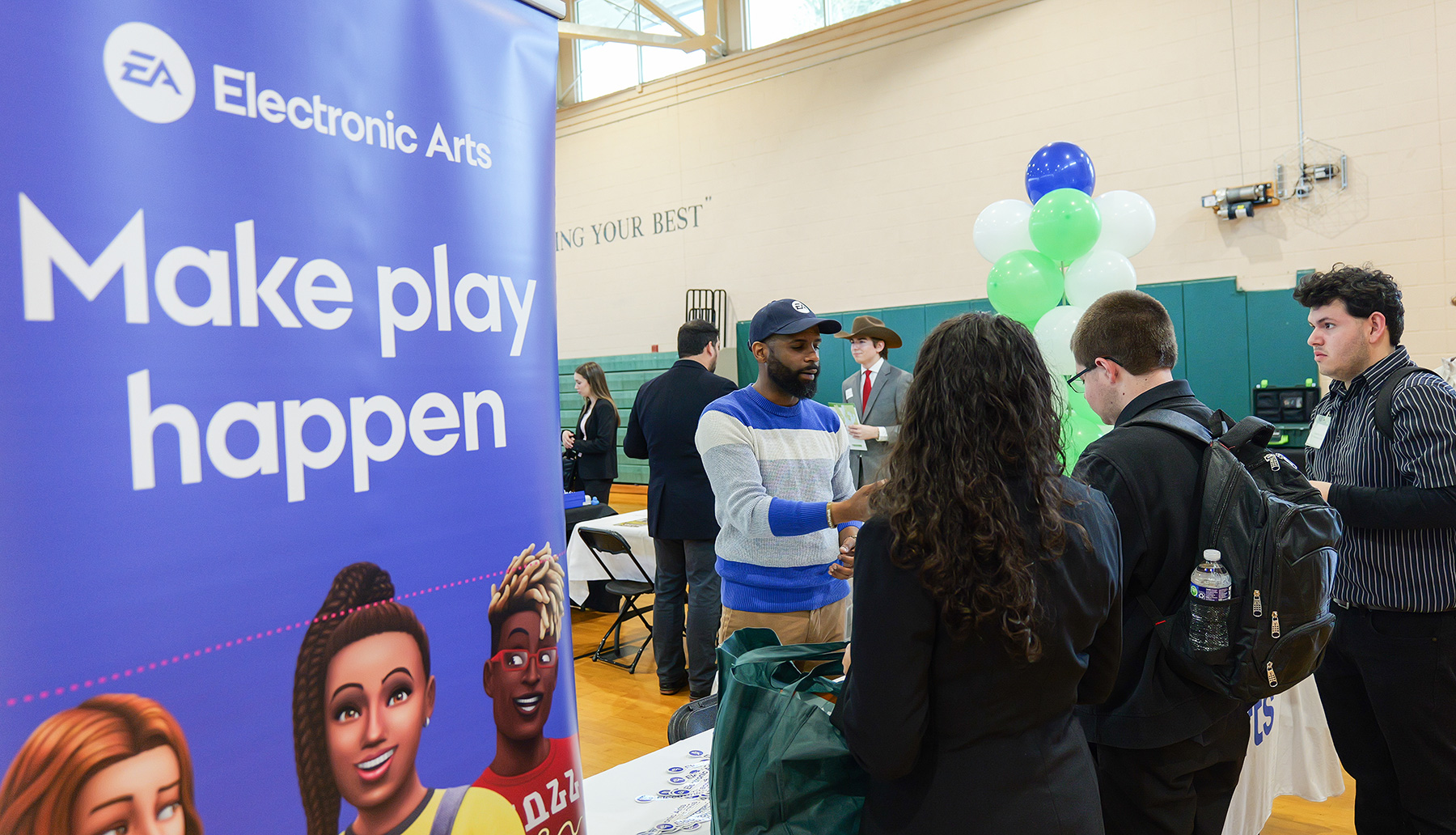 An employee of Electronic Arts talks to college students at a job fair