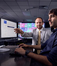 A professor and a student work at a computer.