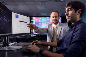 A professor and a student work at a computer.