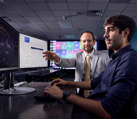 A professor and a student work at a computer.