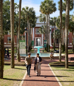 Students walk in Palm Court near the fountain.