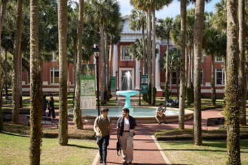 Students walk in Palm Court near the fountain.