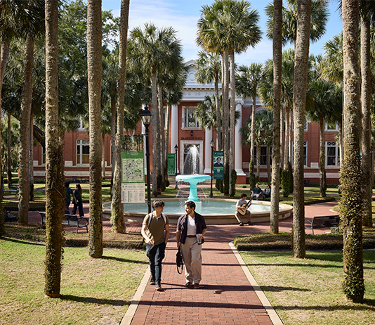 Students walk in Palm Court near the fountain.