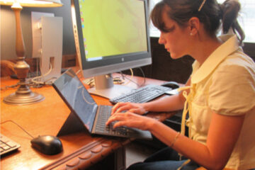 A woman works at her computer in a library