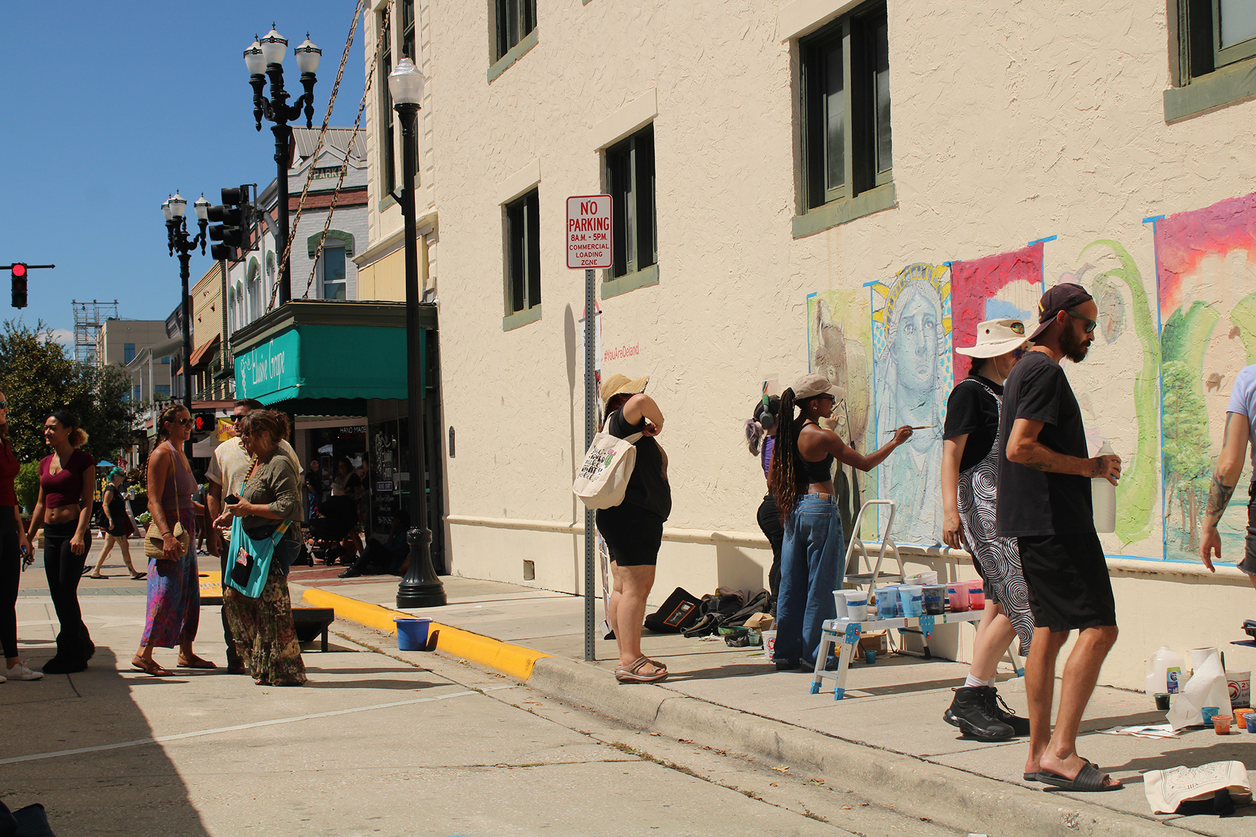 Stetson students painting chalk murals on the Elusive Grape building while passersby look on