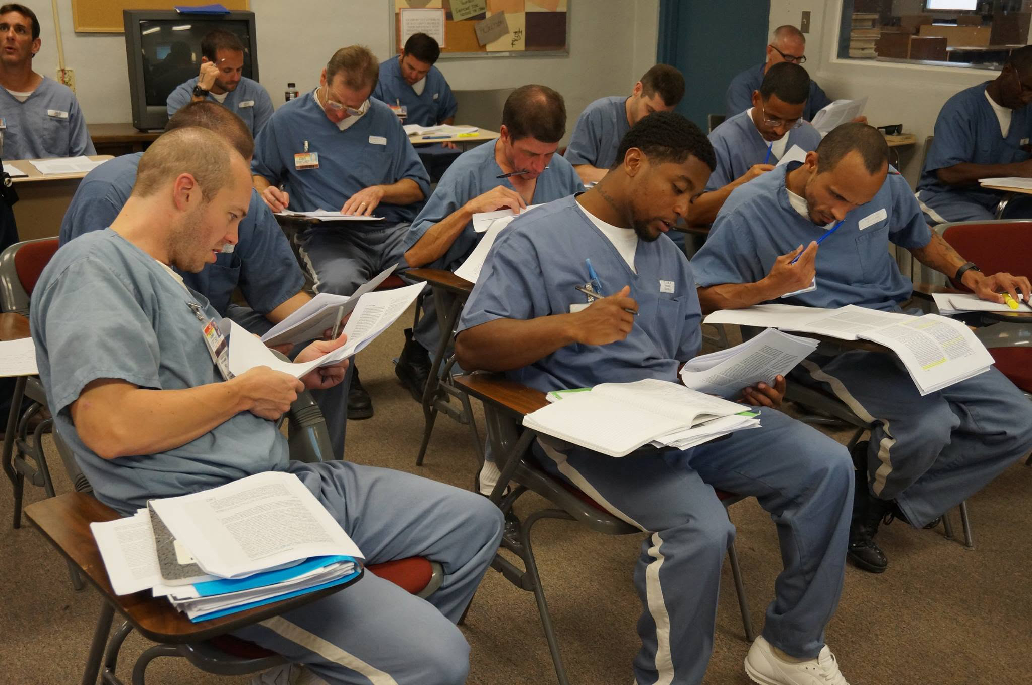 Incarcerated students in a classroom reading course material