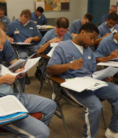 Incarcerated students in a classroom reading course material