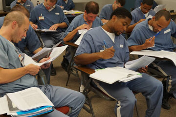 Incarcerated students in a classroom reading course material