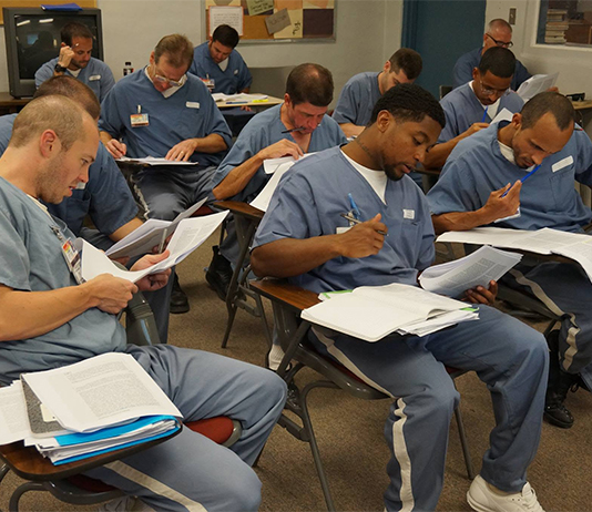 Incarcerated students in a classroom reading course material