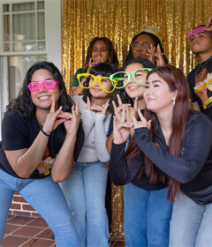 Students posing at a Photo Booth with glittery gold background