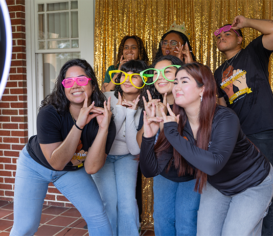 Students posing at a Photo Booth with glittery gold background